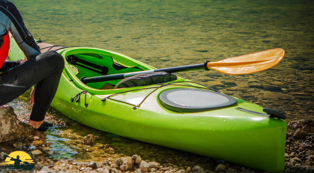 A man sitting besides a kayak