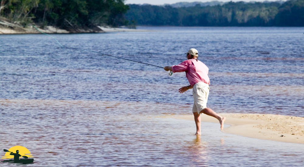 A man is casting a fishing rod on a riverside