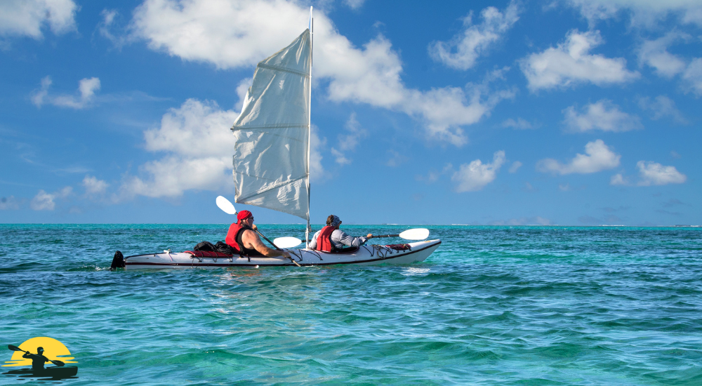 Two men are kayaking with a sail attached kayak