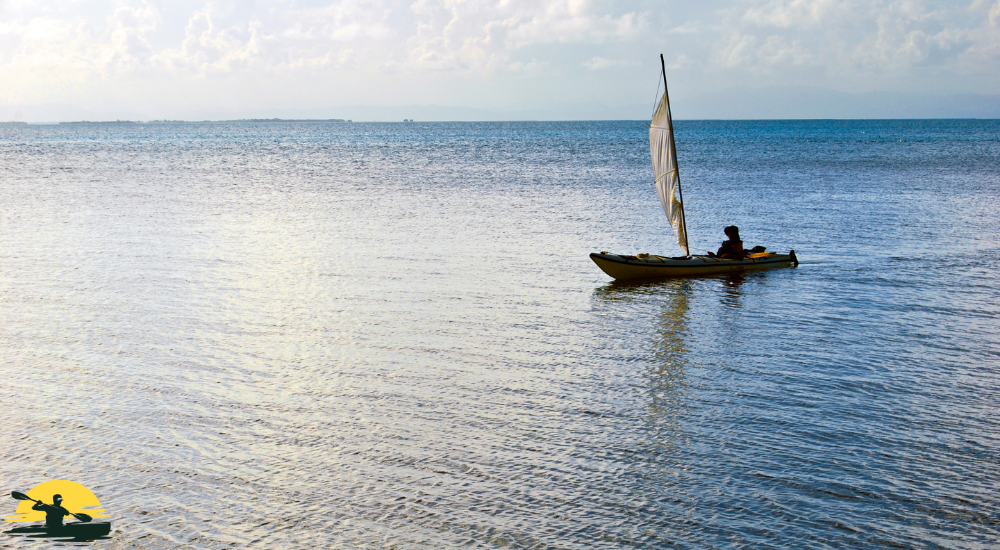 A man is kayaking with sail attached kayak